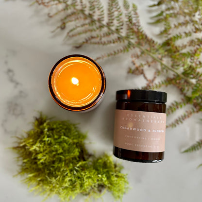 Lit Cedarwood & Juniper essential oil candle surrounded by green moss and woodland ferns.